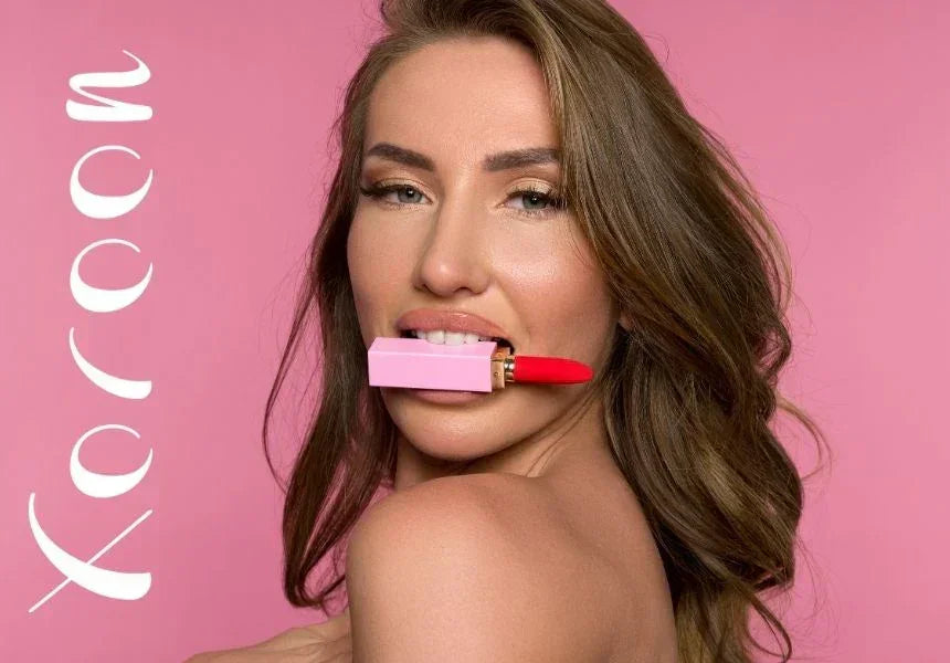 Woman with long brown hair holding bright red lipstick with pink case between her teeth on pink background with Xoçoon text