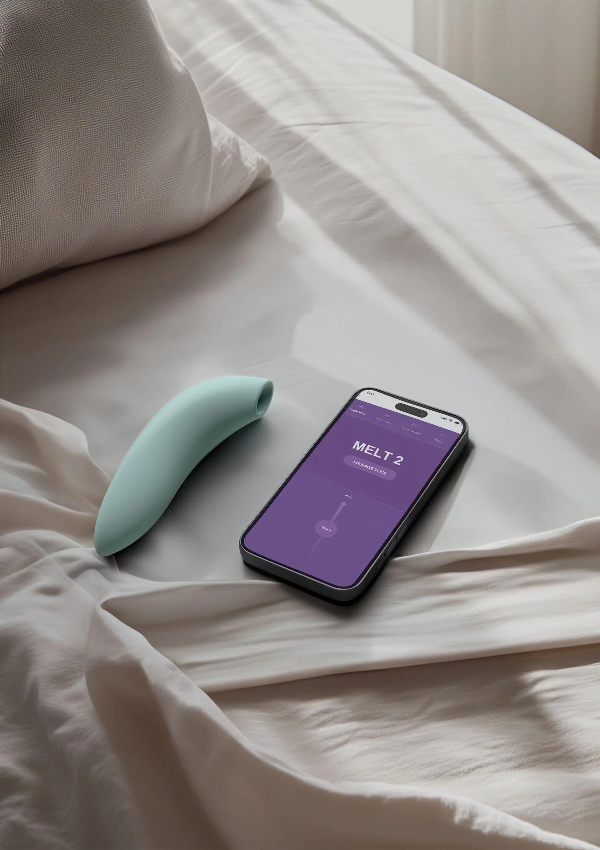 WeVibe Melt 2 airpressure vibrator lichtgroen en smartphone met app op bed