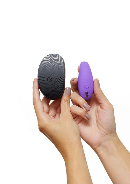 Paarse vibrator met zwarte controller in hand, knop zichtbaar op het apparaat