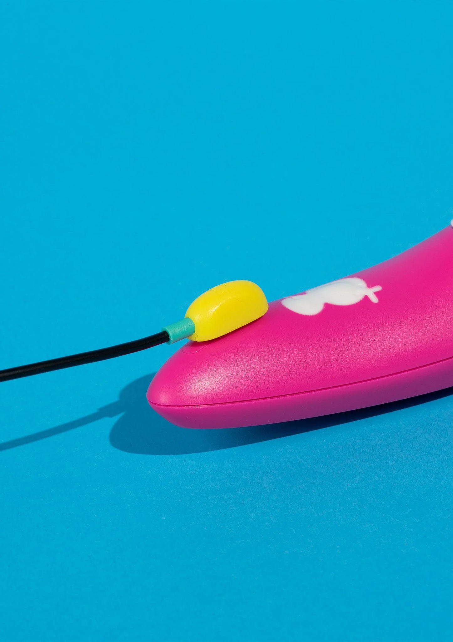 Roze vibrator met gele knop aan zwarte kabel en wit opzetstuk