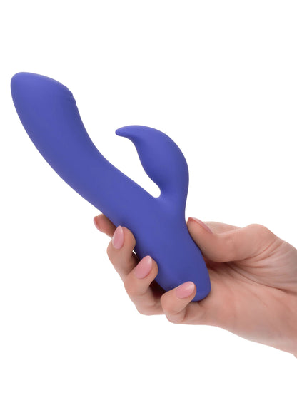 Blauwe siliconen duo-vibrator vastgehouden in de hand, gebogen vorm met opening.