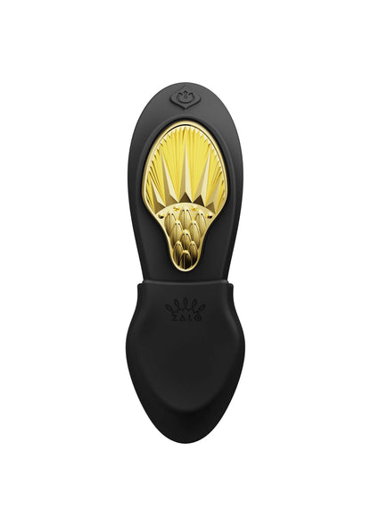 Draagbare vibrator, zwarte tweedelige vorm met open gouden massage-oppervlak vooraan.