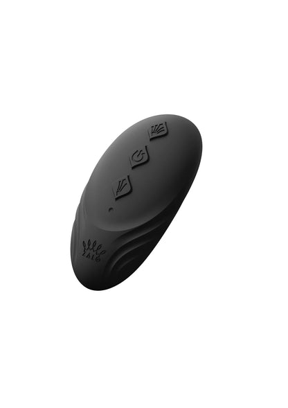 Draagbare vibrator, zwarte ovale achterkant met knoppen en patroonmarkeringen bovenop.
